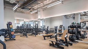 Un gimnasio con diferentes equipos de levantamiento de pesas, bancos y mancuernas.