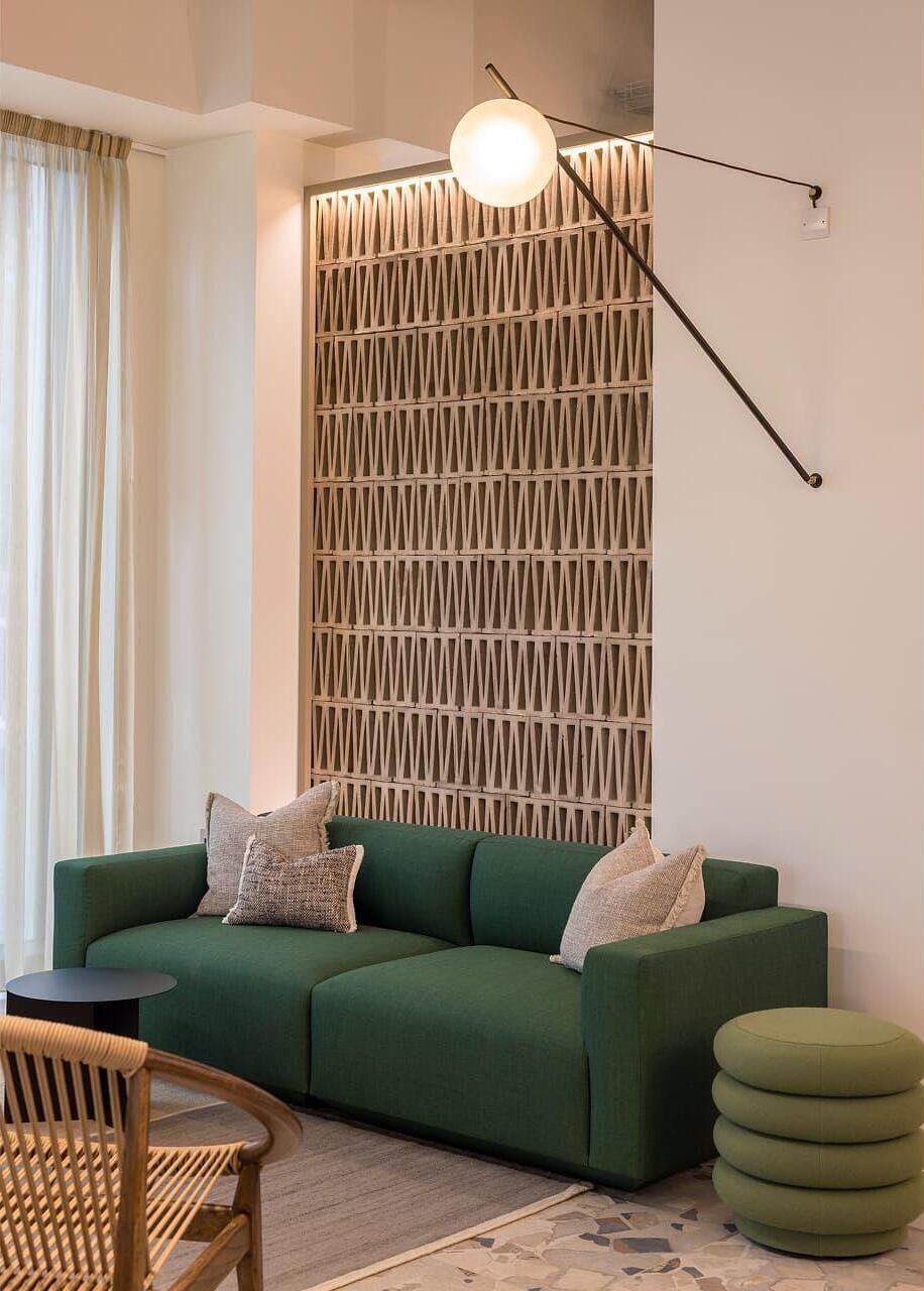 Ein modernes Wohnzimmer mit einem grünen Sofa, einem runden Holzhochentisch und einem grünen Hocker.