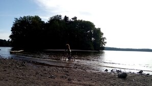 A person riding a bicycle on a rocky shore by a lake with trees in the background. - Chalet by Lac des Settons, Private Garden, Near Hiking & Water Activities (Montsauche-les-Settons)