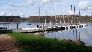 A marina with multiple sailboats docked at a pier, surrounded by calm water and a forested landscape. - Chalet by Lac des Settons, Private Garden, Near Hiking & Water Activities (Montsauche-les-Settons)