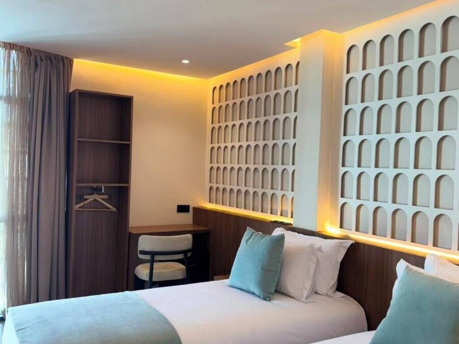 Habitación de hotel con dos camas, un escritorio y un armario.