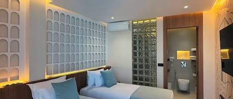 A hotel room with two beds, a bathroom, and a TV.