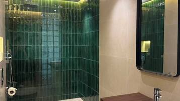 A modern bathroom with a glass-enclosed shower, a white sink, and a mirror.