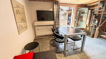 Ein modernes Interieur mit Essbereich, Flachbildfernseher und einer Treppe, die in einen oberen Bereich führt.