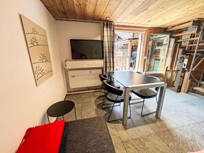 A modern interior with a dining area, a flat-screen TV, and a staircase leading to an upper level.