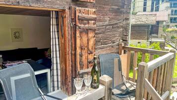 Ein rustikaler Holz-Sitzbereich im Freien mit Tisch, Stühlen und einer Weinflasche.