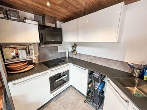 A modern kitchen with white cabinetry, a black stove, and a built-in oven.