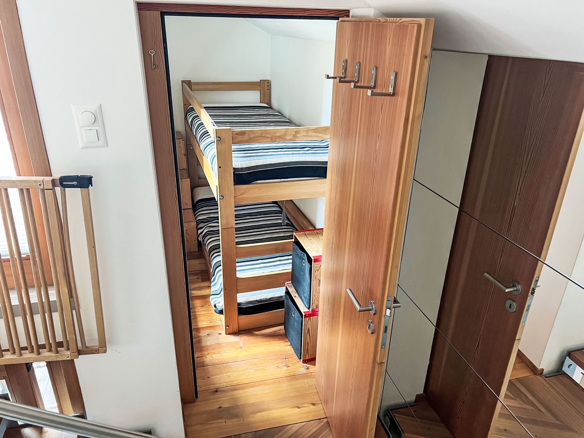 Ein kleines Zimmer mit Etagenbett, Kleiderschrank und einer Tür.