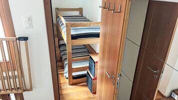 Ein kleines Zimmer mit Etagenbett, Kleiderschrank und einer Tür.