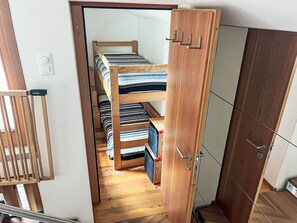 A compact room with a bunk bed, a wardrobe, and a door.