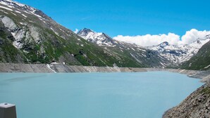 A mountain lake with rocky shores and snow-capped peaks in the background.