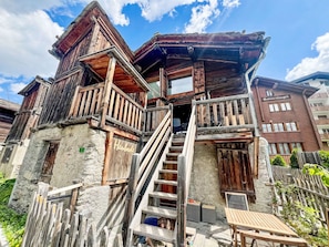 A rustic wooden building with a balcony and a staircase leading to the entrance.