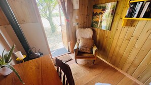 Interior de madera con una silla, una estantería y una puerta que da al exterior.