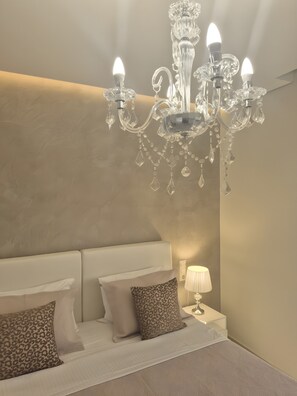 A bedroom with a white bed, a chandelier, and a bedside lamp. - Studio Apartment 'Chriss 101' with Sea View, Wi-Fi and Air Conditioning (Skala Sotiros)