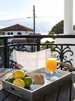 Ein Tablett mit Orangensaft, einer Zitrone, Limette und Keksen auf einem Balkon mit Blick auf Gebäude und einen klaren Himmel.