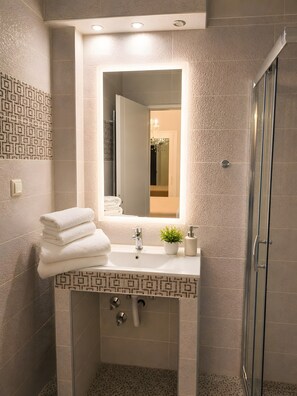Ein modernes Badezimmer mit Waschbecken, Spiegel und einer Duschkabine aus Glas.