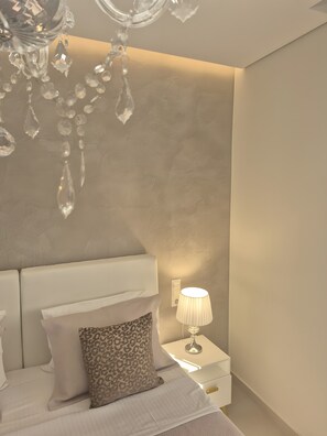 Un dormitorio con cama, mesita de noche, lámpara y candelabro.