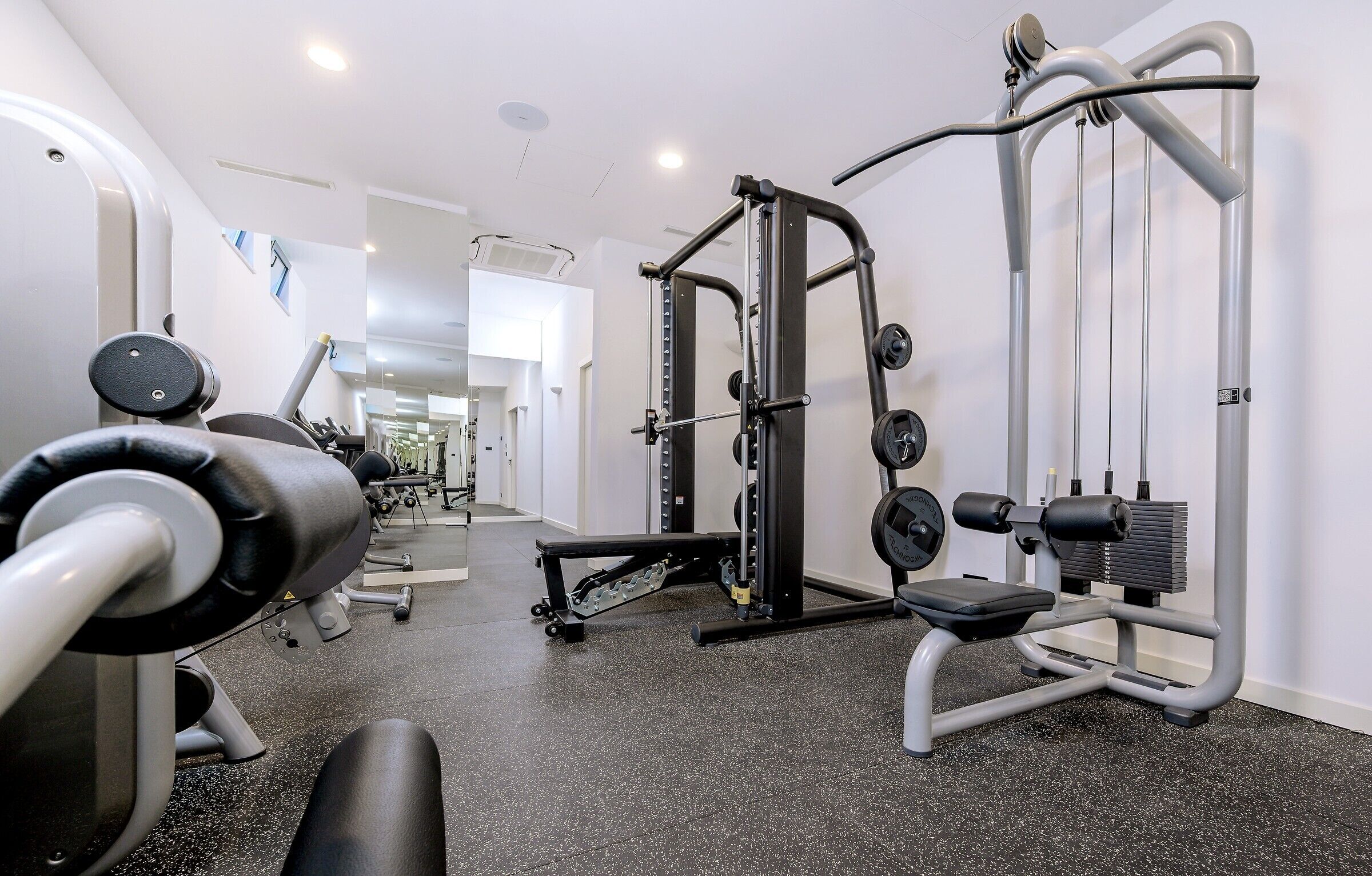 A gym with exercise equipment, a bench, and a weight rack.