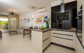 A modern kitchen with a dining area, featuring a central island, built-in appliances, and artwork on the walls. - Green Eden Apartment with Sea View, Wi-Fi, and Underfloor Heating (Split)