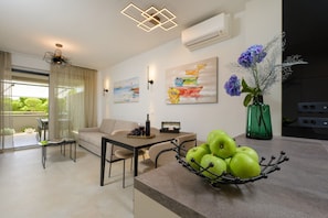 A modern living room with a sofa, dining table, and a fruit bowl. - Green Eden Apartment with Sea View, Wi-Fi, and Underfloor Heating (Split)