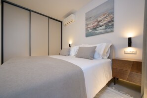 A modern bedroom with a bed, bedside tables, an air conditioning unit, and a painting on the wall. - Green Eden Apartment with Sea View, Wi-Fi, and Underfloor Heating (Split)