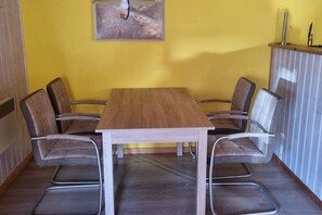 A dining area with a wooden table and six chairs. - Gemutlicher Doppelbungalow im Ferienpark Mirow mit Terrasse (Mirow)