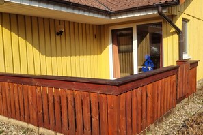 A yellow building with a wooden deck and a window. - Gemutlicher Doppelbungalow im Ferienpark Mirow mit Terrasse (Mirow)