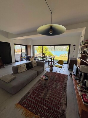 A modern living room with a large sofa, a coffee table, a rug, and a television. - House on the shores of Lake Annecy (Talloires)