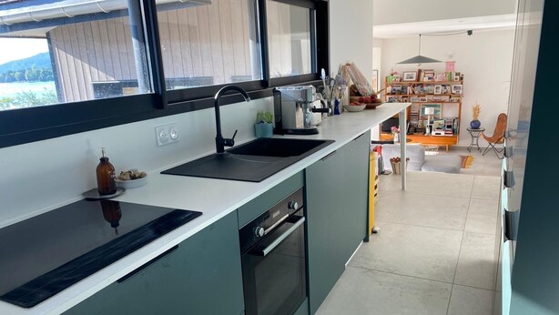 Une cuisine moderne avec un plan de travail noir, un évier et une fenêtre donnant sur un jardin.