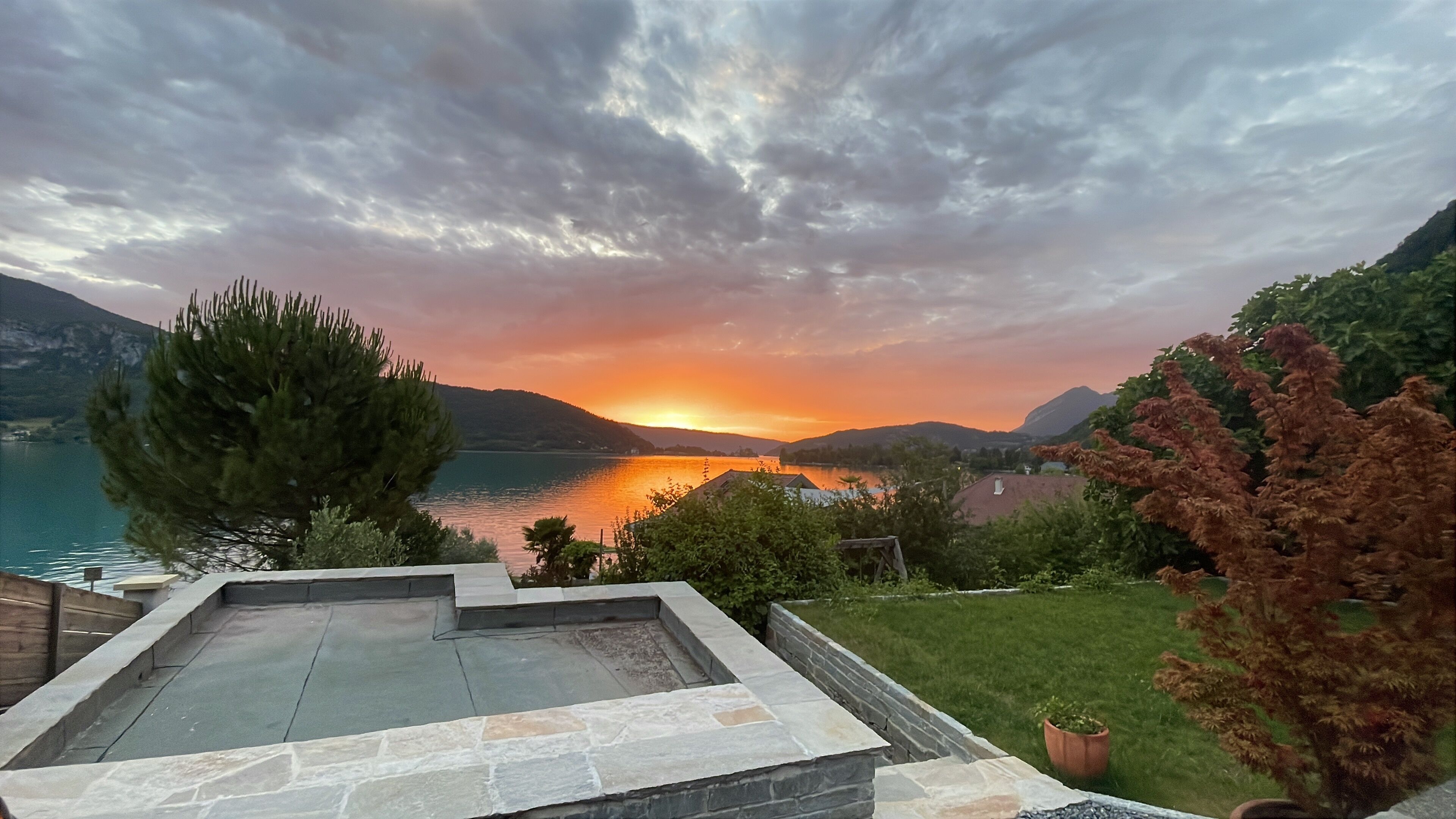A stone pool with a view of a lake and mountains during sunset.