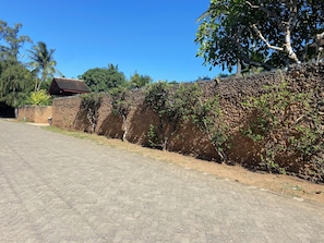 A paved driveway leading to a building with a red roof, surrounded by a stone wall and trees. - Kizakura Homes-Spacious 6-bedroom Villa in Marine Park. Malindi Kenya (Malindi)