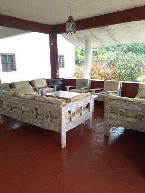 Un espacio de estar al aire libre con mobiliario de madera y suelo de baldosas.