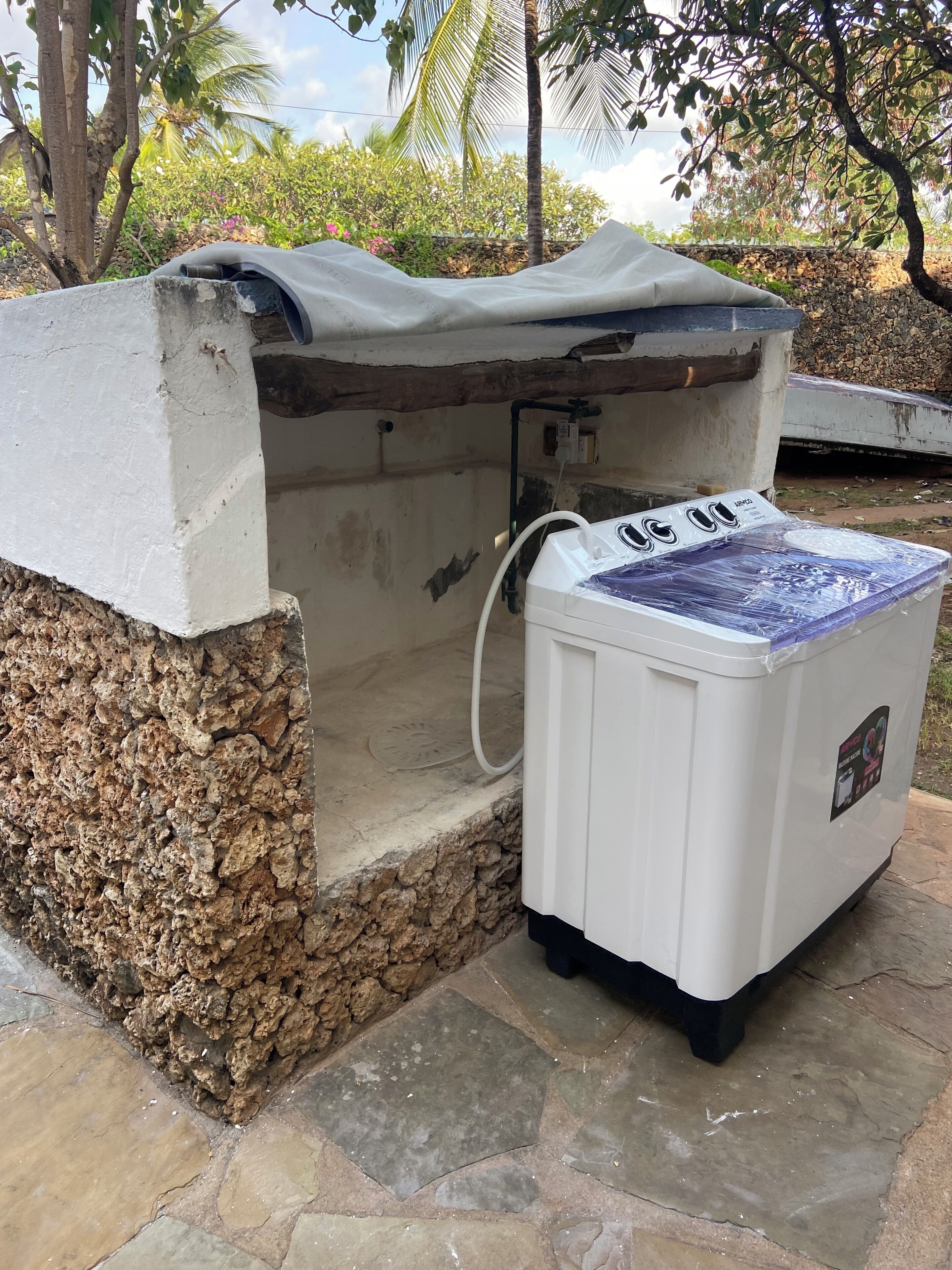 Aquecedor de água em ambiente externo, com parede de pedra e área coberta.