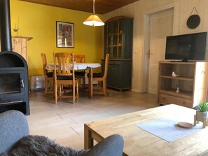 A cozy living room with a fireplace, wooden furniture, a television, and a dining area. - Double Bungalow in Country House Style With Terrace in the Mirow Holiday Park (Mirow)