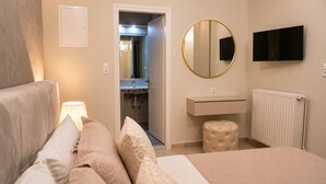 A bedroom with a bed, a bedside table, a round mirror, a TV, a radiator, and a bathroom visible through an open door. - Studio Apartment 'Chrissi 104' with Sea View, Wi-Fi and Air Conditioning (Skala Sotiros)