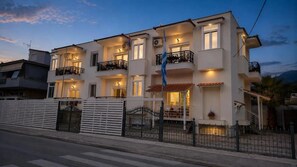 A multi-story residential building with balconies, a flag, and a gated entrance. - Studio Apartment 'Chrissi 104' with Sea View, Wi-Fi and Air Conditioning (Skala Sotiros)
