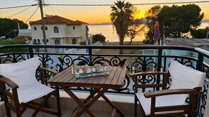 A balcony with a table and chairs, overlooking a body of water and a sunset. - Studio Apartment 'Chrissi 104' with Sea View, Wi-Fi and Air Conditioning (Skala Sotiros)
