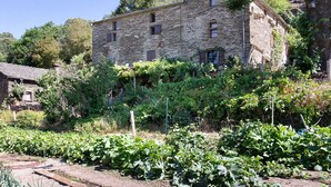 Ein Steinhaus mit vielen Fenstern und einem Garten davor.