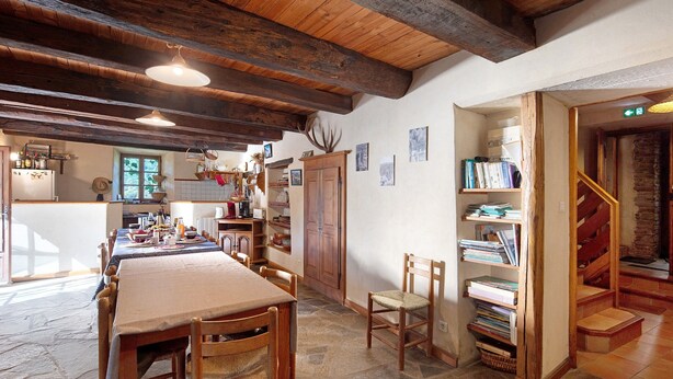 Ein rustikaler Essbereich mit einem langen Holztisch, Stühlen und einer Bücherwand voller Bücher.