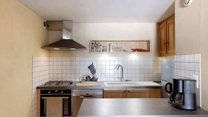 Eine Küche mit Gasherd, Backofen, Spüle und Kaffeemaschine.