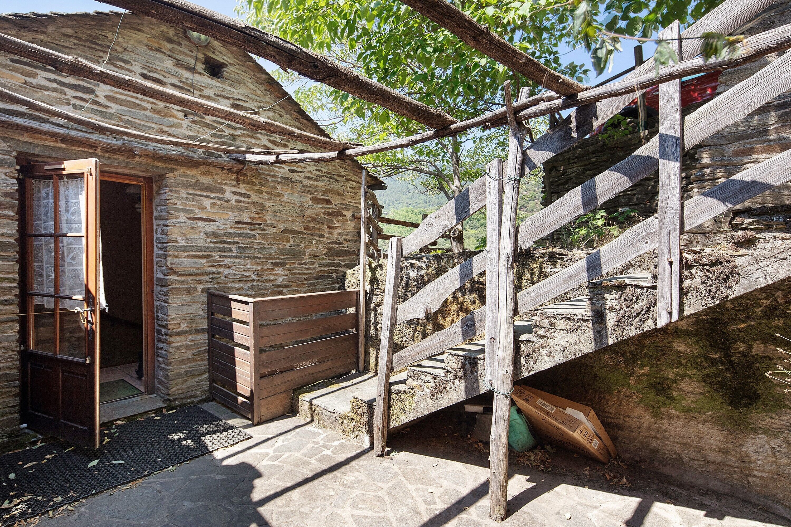 Un edificio rústico de piedra con una escalera de madera que sube a un nivel superior.