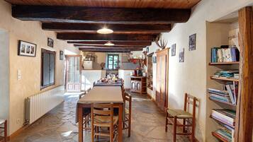 Un comedor rústico con una larga mesa de madera, sillas y piso de piedra.