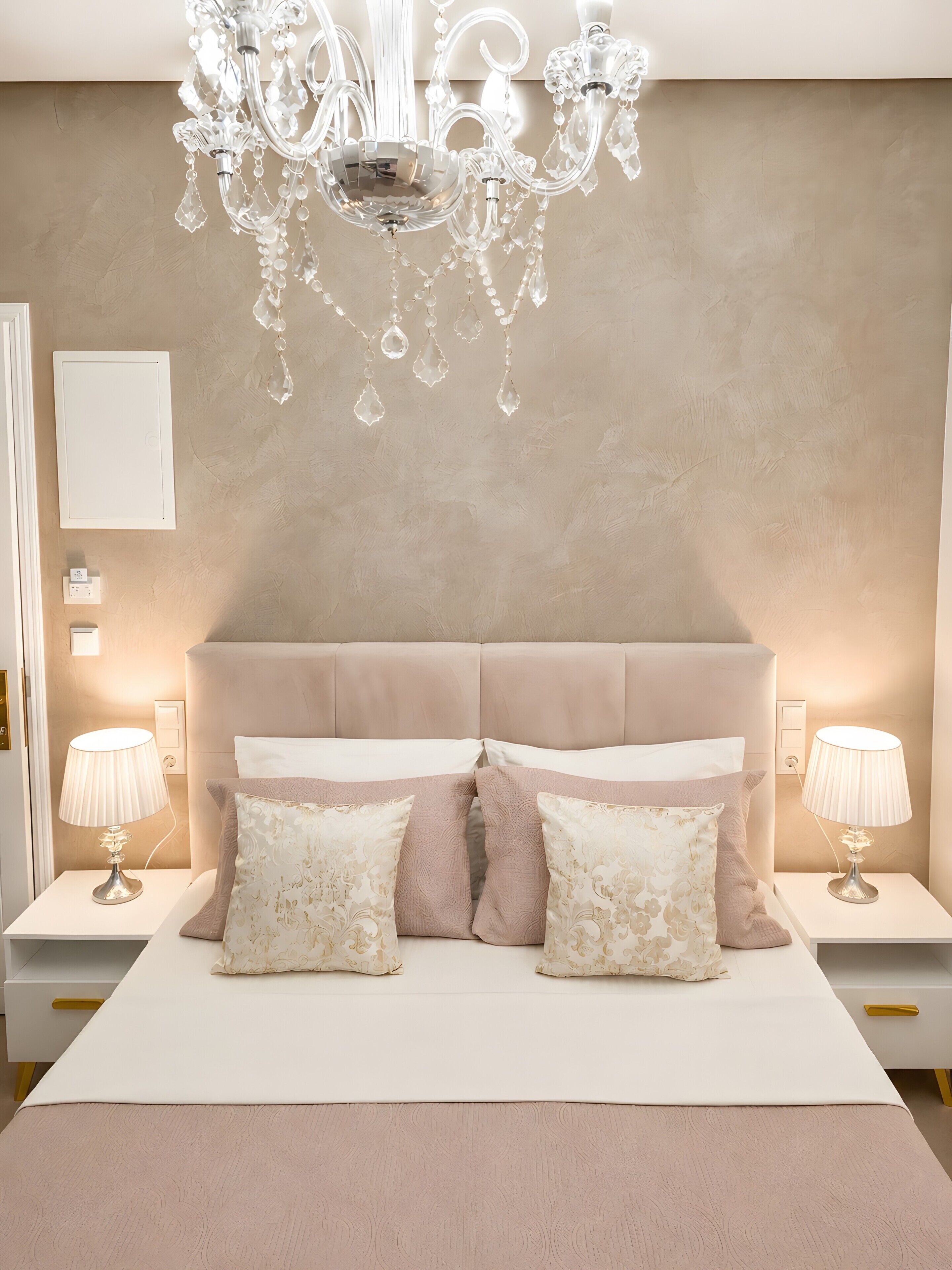 Une chambre à coucher avec un grand lit, deux lampes de chevet, un lustre et un interrupteur fixé au mur.
