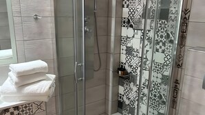 Un baño moderno con ducha envuelta en vidrio, inodoro y lavamanos con toallas apiladas.