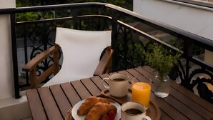 Varanda com mesa posta para o café da manhã, incluindo croissants, café e suco de laranja.