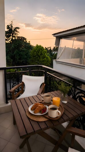 Ein Balkon mit einem Tisch, gedeckt für ein Frühstück, darunter Croissants, Kaffee und Orangensaft.