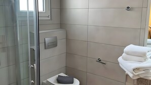 Um banheiro moderno com box de vidro, vaso sanitário e área de pia com toalhas.