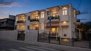 Um edifício residencial com várias andares, varandas, uma bandeira e um portão.