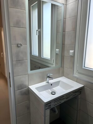 A bathroom with a white sink, a mirror, and a ventilation system. - Studio Apartment 'Chrissi 103' with Sea View, Wi-Fi and Air Conditioning (Skala Sotiros)