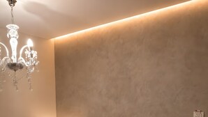 A bedroom with a large bed, a chandelier, a bedside table with a lamp, and a textured wall. - Studio Apartment 'Chrissi 103' with Sea View, Wi-Fi and Air Conditioning (Skala Sotiros)